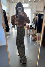 Load image into Gallery viewer, Person taking a mirror selfie wearing a brown top and patterned pants in a clothing store.