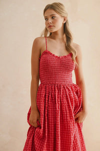 Woman wearing a red checkered dress against a beige background