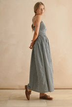 Load image into Gallery viewer, Woman wearing a black and white checkered dress against a beige wall.