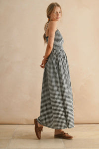 Woman wearing a black and white checkered dress against a beige wall.
