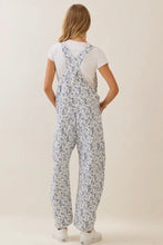 Load image into Gallery viewer, Person wearing a white t-shirt and floral overalls on a plain background