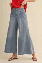 Load image into Gallery viewer, Person wearing light blue wide-leg jeans and a red top on a beige background