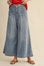 Load image into Gallery viewer, Person wearing light blue wide-leg jeans on a beige background
