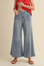 Load image into Gallery viewer, Person wearing blue wide-leg jeans and a red top on a beige background