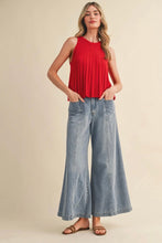 Load image into Gallery viewer, Woman wearing a red sleeveless top and wide-leg jeans on a beige background