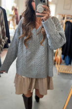 Load image into Gallery viewer, Person wearing a gray cable knit sweater over a beige dress in a clothing store.