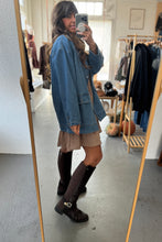 Load image into Gallery viewer, Person taking a mirror selfie wearing a blue oversized sweater, beige skirt, and black boots in a clothing store.