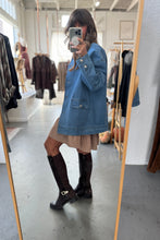 Load image into Gallery viewer, Person wearing a blue denim jacket in a clothing store.