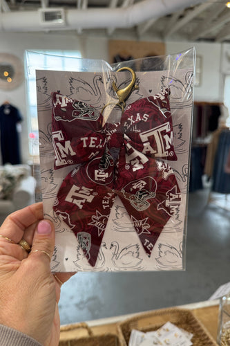 Maroon hair bow with Texas A&M logo held in a clear package.