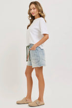 Load image into Gallery viewer, Woman wearing a white t-shirt and denim shorts on a plain background
