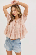 Load image into Gallery viewer, Woman wearing a pink ruffled blouse and denim shorts on a white background