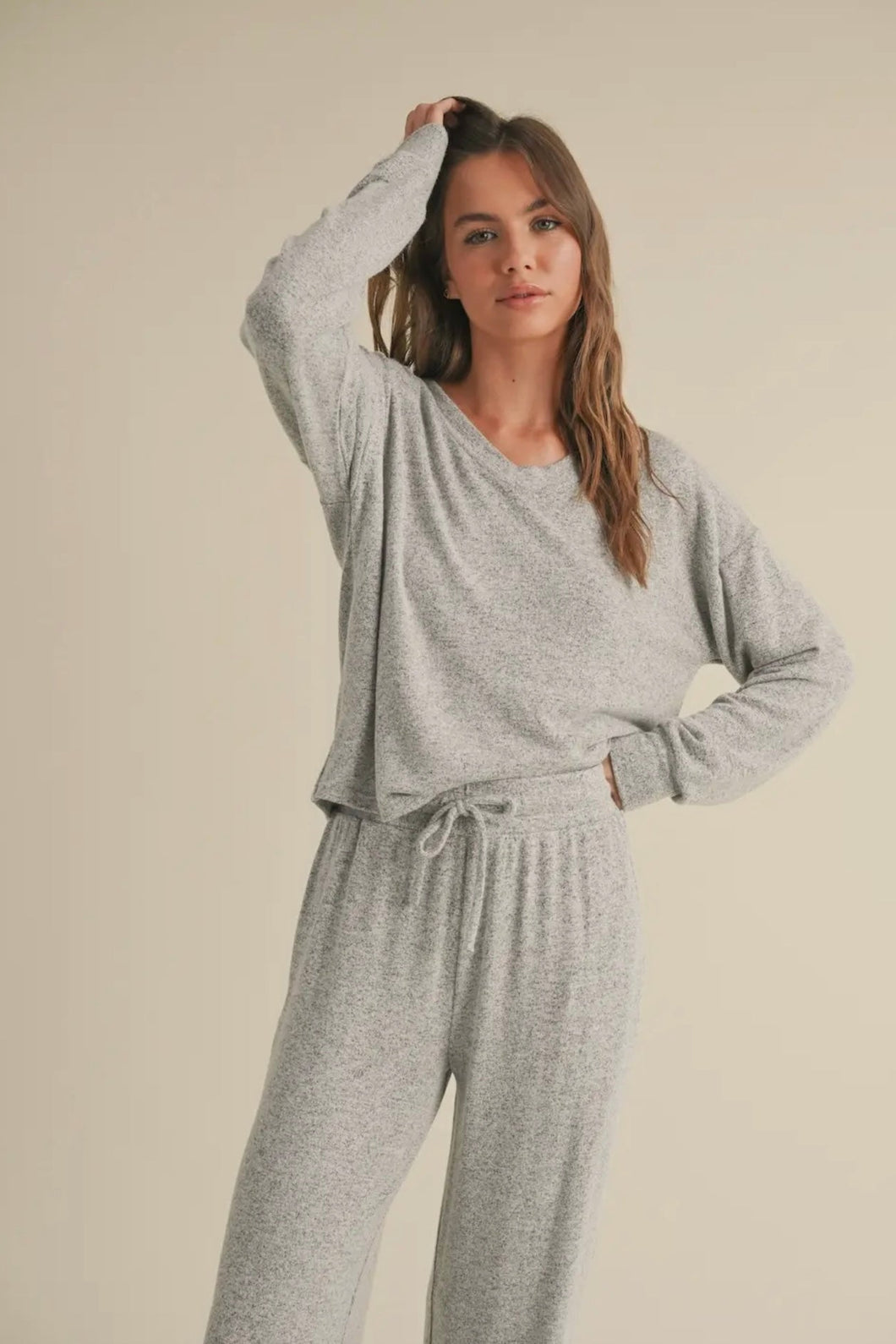 Woman wearing a gray pajama set against a beige background