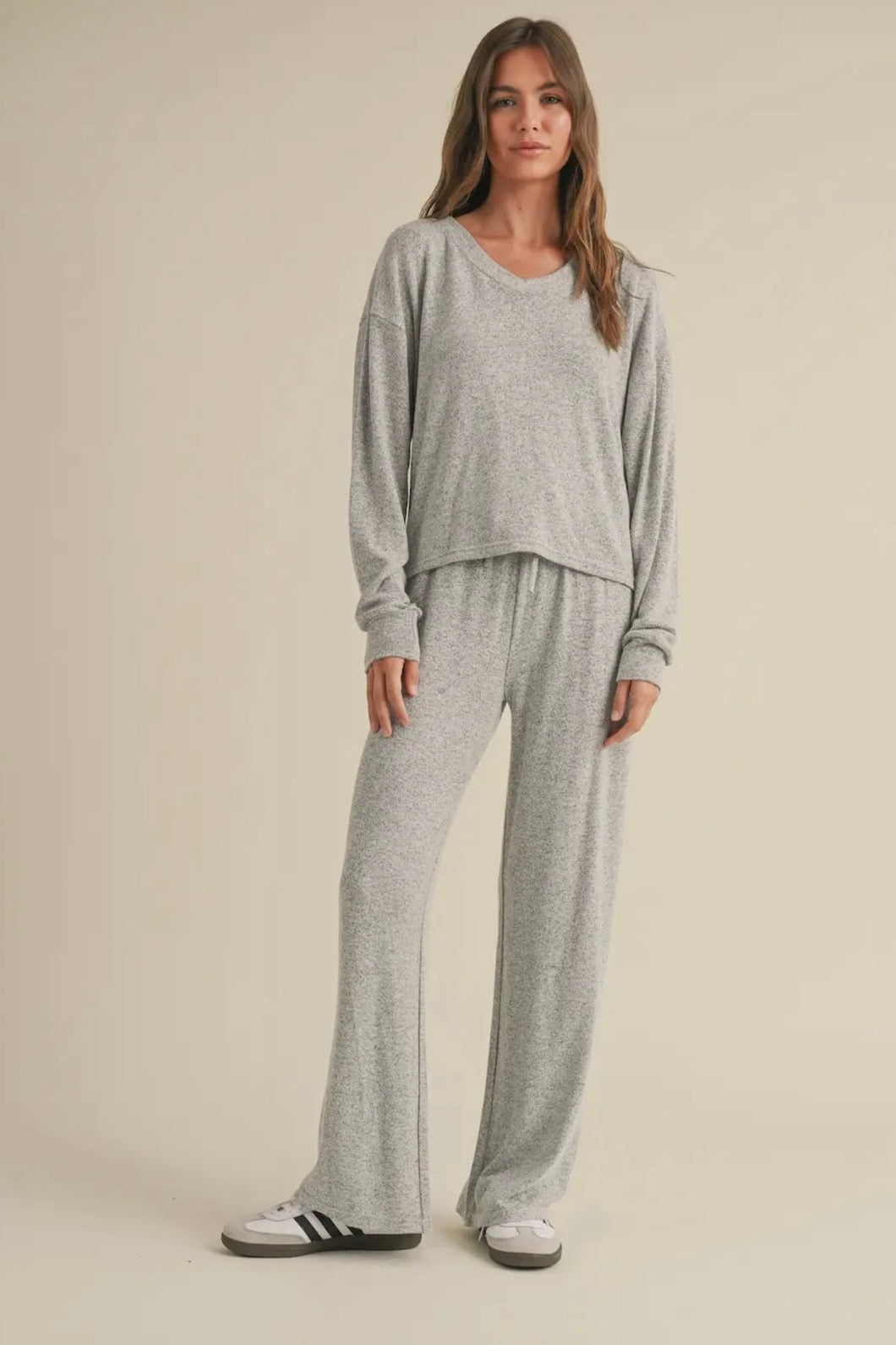 Woman wearing a gray loungewear set on a beige background