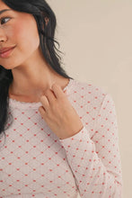 Load image into Gallery viewer, Woman wearing a light pink long-sleeve top with a subtle pattern against a beige background