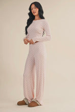 Load image into Gallery viewer, Woman wearing a light pink floral jumpsuit on a beige background