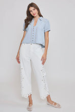 Load image into Gallery viewer, Woman wearing a light blue denim shirt and white pants with lace details on a plain background