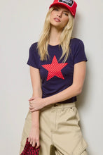 Load image into Gallery viewer, Woman wearing a navy t-shirt with a red star design, beige pants, and a red cap against a plain background