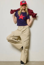 Load image into Gallery viewer, Person wearing a red star t-shirt, beige cargo pants, and a red cap with a white logo.