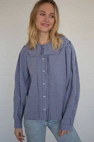 Woman wearing a blue and white checkered shirt against a plain background