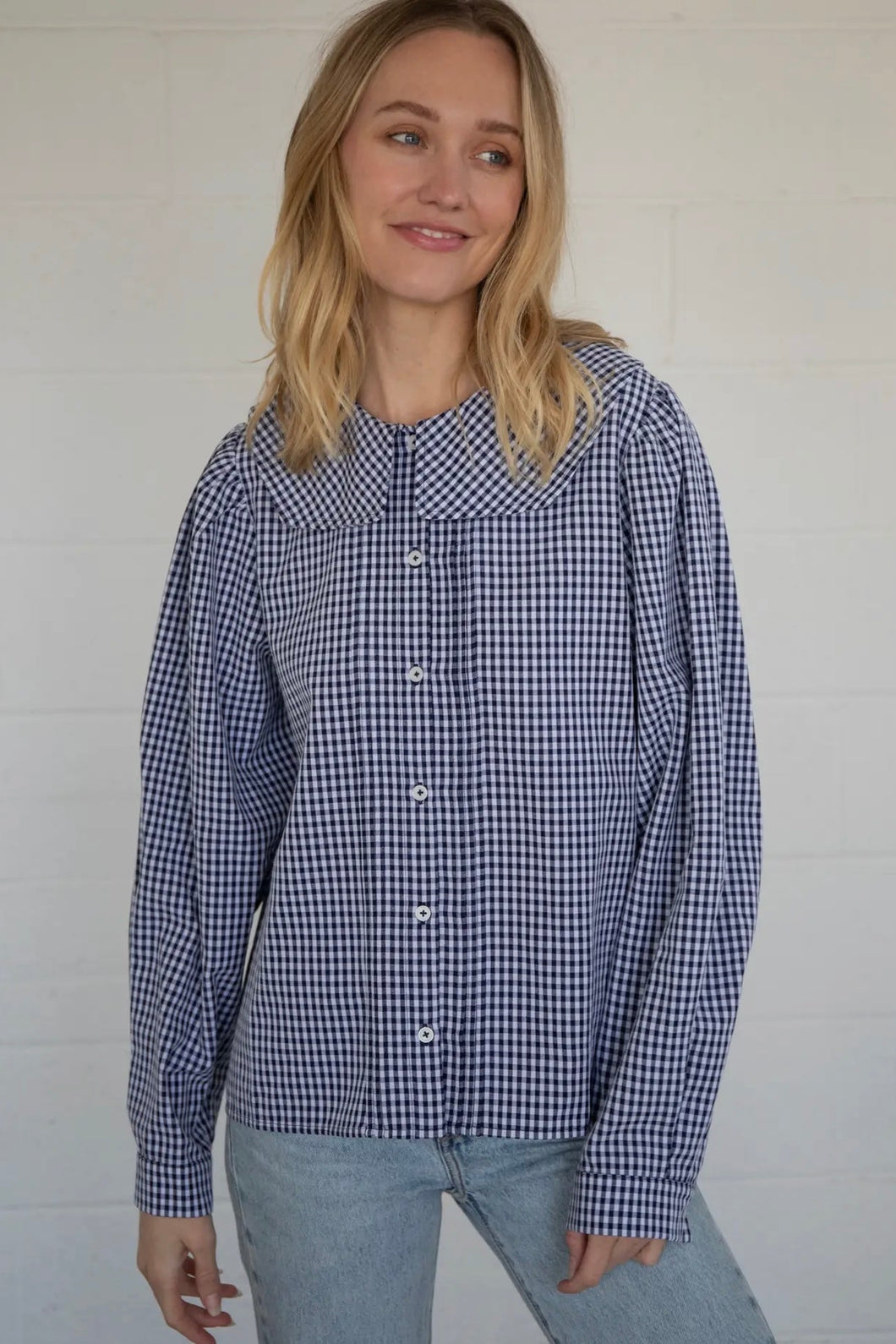Woman wearing a blue and white checkered shirt against a plain background