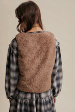 Load image into Gallery viewer, Person wearing a brown fleece vest over a plaid shirt and skirt on a beige background