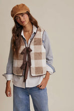 Load image into Gallery viewer, Woman wearing a plaid vest, shirt, jeans, and cap on a beige background