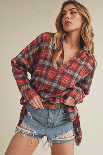 Woman wearing a red plaid shirt and denim shorts on a plain background