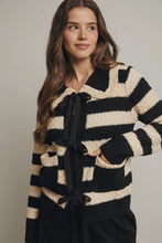 Load image into Gallery viewer, Woman wearing a black and beige striped sweater with a tie detail on a plain background