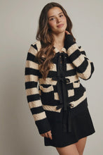 Load image into Gallery viewer, Woman wearing a black and beige striped sweater with a tie detail on a plain background