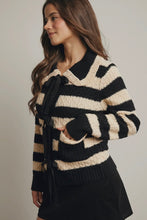 Load image into Gallery viewer, Woman wearing a black and beige striped sweater with a tie detail on a plain background