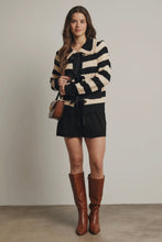 Load image into Gallery viewer, Woman wearing a black and beige striped sweater with a belt, black skirt, and brown knee-high boots against a plain background.