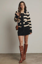 Load image into Gallery viewer, Woman wearing a black and beige striped sweater, black skirt, and brown knee-high boots against a plain background.