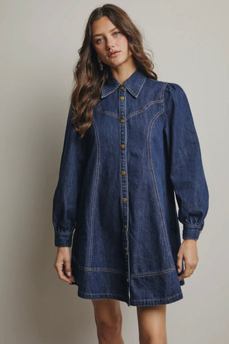 Woman wearing a denim dress against a plain background