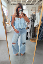 Load image into Gallery viewer, Woman taking a mirror selfie wearing a light blue top and jeans in a clothing store.