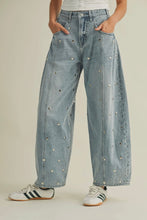 Load image into Gallery viewer, Person wearing light blue denim jeans with decorative studs on a neutral background