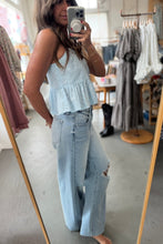 Load image into Gallery viewer, Person taking a mirror selfie wearing a light blue peplum top and jeans in a clothing store.