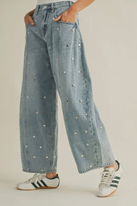 Light blue jeans with decorative studs worn by a person on a plain background