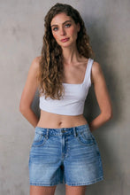Load image into Gallery viewer, Woman wearing a white tank top and denim shorts against a gray background