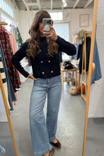 Load image into Gallery viewer, Person taking a mirror selfie wearing a black jacket and blue jeans in a clothing store.
