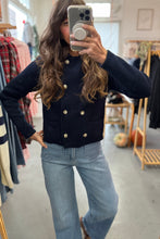Load image into Gallery viewer, Person wearing a navy blue jacket with gold buttons and light blue jeans in a clothing store.