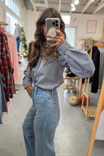 Load image into Gallery viewer, Person taking a mirror selfie wearing a checkered shirt and jeans in a clothing store.