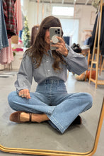 Load image into Gallery viewer, Woman taking a mirror selfie wearing a checkered shirt and blue jeans in a clothing store.