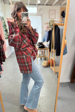 Load image into Gallery viewer, Person wearing a red plaid shirt and blue jeans in a clothing store.