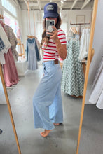 Load image into Gallery viewer, Person taking a mirror selfie wearing a red and white striped shirt, blue jeans, and a blue cap in a clothing store.