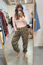 Load image into Gallery viewer, Person taking a mirror selfie wearing a pink sweater and camouflage pants in a clothing store.