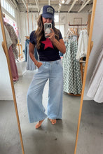 Load image into Gallery viewer, Person taking a mirror selfie wearing a navy t-shirt with a red star, light blue jeans, and a navy cap in a clothing store.