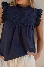 Load image into Gallery viewer, Navy blue top with ruffled shoulders worn by a person against a neutral background