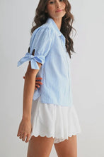 Load image into Gallery viewer, Woman wearing a light blue striped shirt and white shorts on a plain background