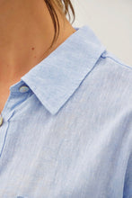 Load image into Gallery viewer, Close-up of a light blue shirt with a collar and button detail.