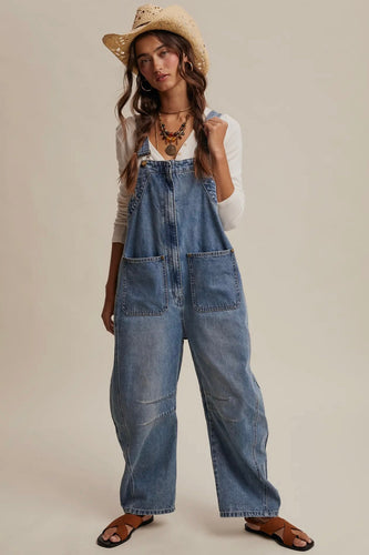 Woman wearing denim overalls and a straw hat on a beige background